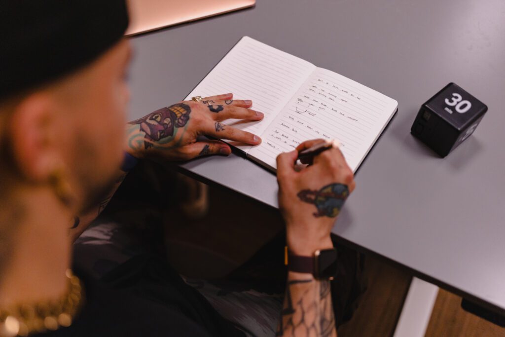 Tattooed hands writing in journal